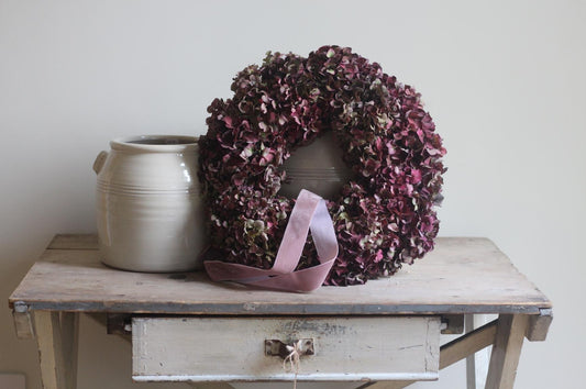 Pod & Pip's beautiful wreath displayed on a vintage table with pottery